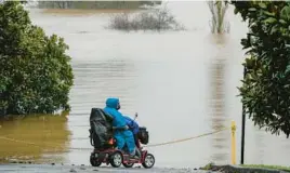  ?? MARK BAKER/AP ?? A woman looks over inundated farmland Monday near Sydney as Australia’s largest city braces for its fourth and possibly worst round of flooding in 18 months.