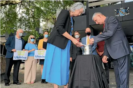  ?? MARK TAYLOR/STUFF ?? Councillor­s watch on as Hamilton mayor Paula Southgate and the Ukranian community’s Yuriy Gladun light a candle in memory of all those Ukrainians who have suffered because of the war.