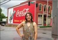  ?? SUBMITTED ?? Victoria Hutcheson poses in front of the historic Coca-Cola mural in downtown Batesville. She helped revitalize the mural before graduating in May.