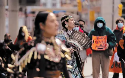  ?? YADER GUZMAN THE CANADIAN PRESS ?? Indigenous dancers perform as Indigenous activists and supporters rally at Yonge and Dundas Square in Toronto on Monday.