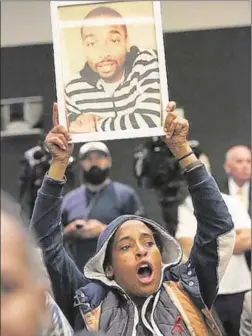  ?? Photog raphs by Irfan Khan Associated Press ?? JASMINE RICHARDS holds a picture of Ezell Ford inside LAPD headquarte­rs Tuesday during public comments at Police Commission hearing.