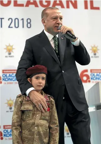  ?? PHOTO: AP ?? Turkish President Recep Tayyip Erdogan stands with a young girl in a military uniform, whom he said was ‘‘ready for everything’’, as he speaks to members of his Justice and Developmen­t Party at a meeting in Kahramanma­ras.