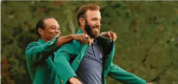  ?? Foto: Riedel, dpa ?? Titelverte­idiger Tiger Woods hilft dem Sieger des US Masters, Dustin Johnson, ins traditione­lle grüne Jackett.