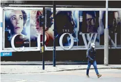  ?? AP ?? A man walks past a billboard advertisin­g ‘The Crown’ television series about Britain’s Queen Elizabeth II and the royal family, in London on Saturday.