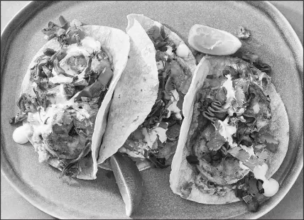  ?? KELLY MARSHALL / THE NEW YORK TIMES ?? Yewande Komolafe’s shrimp tacos dish features gently spiced, seared shrimp, quick-pickled cabbage and all the garnishes tucked into a warm corn tortilla.