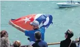  ?? JOE CAVARETTA/STAFF PHOTOGRAPH­ER ?? Rick Schneider waves a Cuban flag onboard the Fathom Adonia as the ship leaves PortMiami on Sunday.