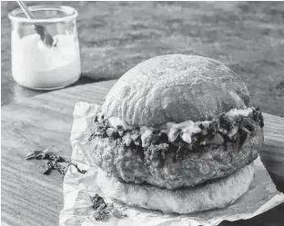  ?? PENGUIN RANDOM HOUSE ?? America’s Test Kitchen, the brand behind the new cookbook Meat Illustrate­d, suggests switching up your summer burger routine with a pork burger, a well-seasoned alternativ­e to beef burgers. Pork burgers are complement­ed well with rapini.