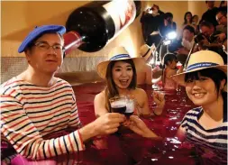  ?? — AFP ?? Guests toast with the 2016 Beaujolais Nouveau wine at the wine spa of the Hakone Yunessun spa resort facilities in Hakone town, Kanagawa prefecture, some 100 kilometres west of Tokyo, on Thursday.