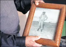  ??  ?? Primm, a 98-year-old veteran of World War II, the Korean War and Vietnam, holds up a photo taken during his service in Vietnam.