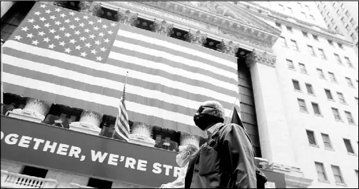 ?? REUTERS ?? Traders walk past the New York Stock Exchange as the building opens for the first time since March while the outbreak of the coronaviru­s disease continues in the Manhattan borough of New York.