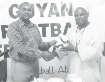  ??  ?? Guyana Football Federation (GFF) president Wayne Forde presents the footballs to one of the organisers of the 10th annual St Romain Memorial games.