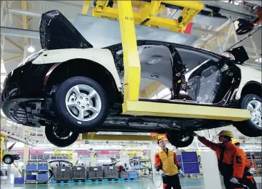  ?? BLOOMBERG ?? Geely Automobile Holdings Ltd employees assemble a sedan on the production line at the company’s factory in Cixi, Zhejiang province.