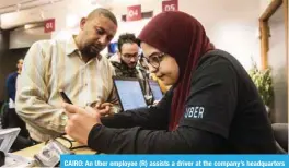  ??  ?? CAIRO: An Uber employee (R) assists a driver at the company’s headquarte­rs in the Egyptian capital. — AFP