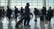  ?? NG HAN GUAN — THE ASSOCIATED PRESS ?? Passengers wearing face masks to protect against the spread of the coronaviru­s line up at a boarding gate at Wuhan Tianhe Internatio­nal Airport in Wuhan in central China’s Hubei Province Thursday.