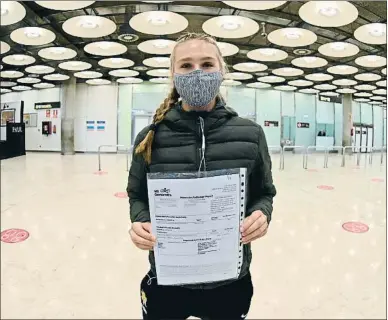  ?? FERNANDO VILLAR / EFE ?? Una turista extranjera muestra el resultado de su PCR al llegar al aeropuerto de Barajas, en Madrid