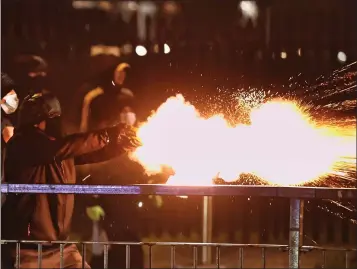  ??  ?? Youths let off fireworks at the PSNI during unrest in Belfast. Top right, Boris Johnson has enraged unionists, while Health Minister Robin Swann has won praise