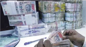  ?? — AFP ?? A bank employee counts rupee currency notes in Mumbai.