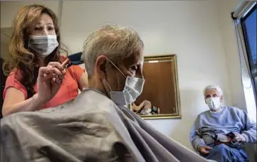  ?? MEL MELCON Los Angeles Times ?? KATHY LY, left, a hairstylis­t at the Headline Salon in Woodland Hills, gives a cut to Gerri Gold, 81. At right is Gold’s husband, Hal Gold, 95. Mask-wearing guidelines will now probably be determined at the local level.