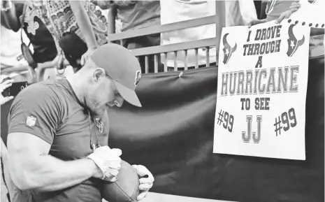  ?? BUTCH DILL, AP ?? The Texans’ J.J. Watt signs autographs for fans holding signs referencin­g Hurricane Harvey on Saturday in New Orleans.