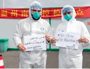  ??  ?? Pakistani doctor Hamad Abdul Zahir (left) and his wife Hosany Sumayyah, who have worked as doctors in China for years, express their wish for an early victory for Chinese people in the fight against the epidemic in Arabic, Urdu, and English at a novel coronaviru­s prevention and control checkpoint in Wenzhou, Zhejiang Province, on February 8.