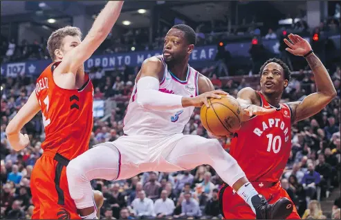  ?? MARK BLINCH/THE CANADIAN PRESS ?? Jakob Poeltl (left) and DeMar DeRozan defend against Dwyane Wade during the second half of the Raptors’ victory over the Miami Heat last night at the Air Canada Centre. DeRozan led all Toronto players with 27 points.