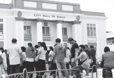 ??  ?? CITY Hall employees evacuate the decades-old building and stay at the open space of Quezon Park following the earthquake that joggled Davao City and other parts of Mindanao on Tuesday morning. BING GONZALES