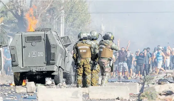  ?? AFP ?? Protestas. Un grupo de carabinero­s busca contener a decenas de habitantes, en los alrededore­s de Santiago, que reclaman mejor atención.