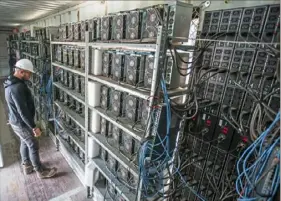  ??  ?? Chris Radwanski, data center supervisor, checks on Bitcoin-mining machines in a shipping container July 23 behind the Scrubgrass Generating Plant.