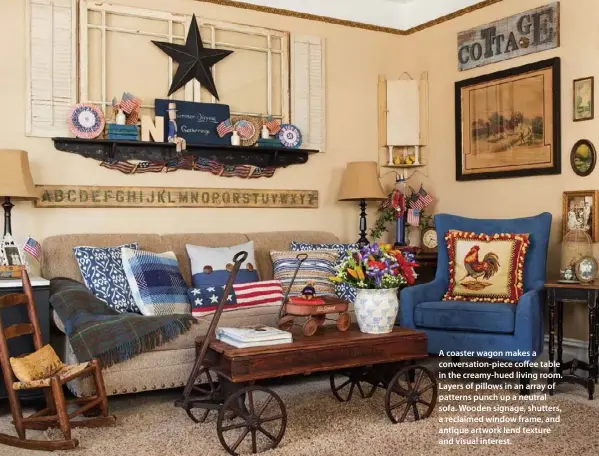  ??  ?? A coaster wagon makes a conversati­on-piece coffee table in the creamy-hued living room. Layers of pillows in an array of patterns punch up a neutral sofa. Wooden signage, shutters, a reclaimed window frame, and antique artwork lend texture and visual...