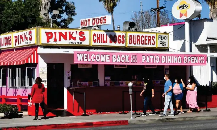  ?? Photograph: Frederic J Brown/AFP/Getty Images ?? People make their way to Pink’s Hot Dogs on the reopening day of the iconic Los Angeles restaurant on 1 March 2021 in California.