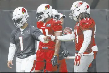  ?? Ross D. Franklin The Associated Press ?? Cardinals quarterbac­k Kyler Murray (1) gets a fist bump from receiver Larry Fitzgerald after the two connected on a pass completion during practice Friday in Glendale, Ariz.