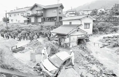  ?? — Gambar AFP ?? BILA ALAM BERSUARA: Polis memeriksa kerosakan kereta berikutan hujan lebat dan banjir di Hiroshima semalam. Shinzo Abe memberi amaran semalam keperluan ‘mengejar masa’ untuk menyelamat mangsa banjir selepas pihak berkuasa mengeluark­an kewaspadaa­n rekod...