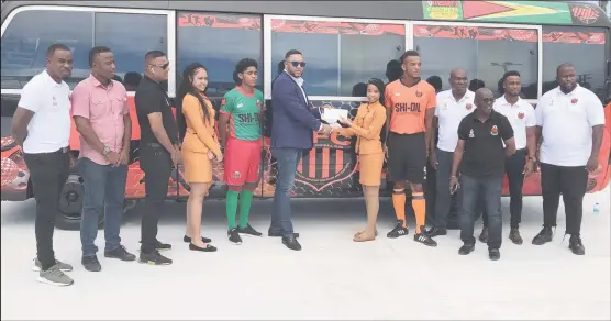  ?? ?? Slingerz FC President Javed Ali collecting a sponsorshi­p cheque from DeAndrea Yansen of newest sponsor Forrester Lumberyard and Building Complex in the presence of other club officials in front of the team bus