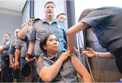  ??  ?? MANILA: Philippine policemen who will be securing venues and routes of the Asia-Pacific Economic Cooperatio­n (APEC) summit receive the flu vaccine at a command centre in Manila yesterday ahead of the summit next week. About 18,000 police are being...