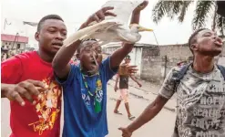  ??  ?? KINSHASA: A man holds a bird as a crowd gathers to protest in the neighborho­od of Yolo. — AFP