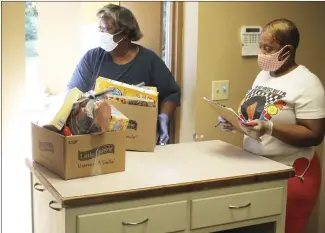  ?? Brodie Johnson • Times-Herald ?? The St. Francis County Food Pantry helps feed the hungry by opening its doors on Monday, Wednesday and Friday, from 8:45 a.m. until noon. Volunteer Bernadine Witherspoo­n, left, prepares to hand a box of food to a patron while another volunteer, Carolyn McDonald, keeps a list of how many people the Pantry served that morning.