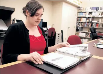  ?? LAURA BARTON/WELLAND TRIBUNE ?? Abbey Stansfield, program coordinato­r for the Port Colborne Heritage and Marine Museum's oral history project, flips through the pages of some of the history the L.R. Wilson Heritage Research Archives already has collected.