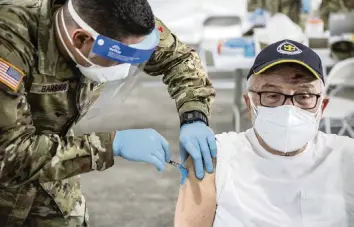  ?? AL DIAZ adiaz@miamiheral­d.com ?? Issac Chanavich, 82, is injected with a COVID-19 vaccine by a U.S. Army medic at a FEMA vaccinatio­n site on Wednesday at Miami Dade College’s North Campus.