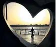  ?? HASAN JAMALI/THE ASSOCIATED PRESS ?? A Saudi woman seen through a heart-shaped statue walks along an inlet of the Red Sea in Jiddah, Saudi Arabia on May 11, 2014. A young Saudi woman has sparked a sensation online by posting a video of herself in a miniskirt and crop top walking around in...