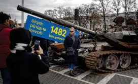  ?? MINDAUGAS KULBIS / ASSOCIATED PRESS ?? A woman poses for a photo in front of a destroyed Russian tank installed to mark the one-year anniversar­y of Russia’s full-scale invasion of Ukraine, in Vilnius, Lithuania, on Wednesday. The banner reads “Send money to fight.”