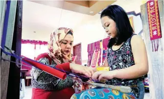  ??  ?? Salika Maguindana­oSamad helps her daughter Hajar in untangling threads tied in a loom before she starts weaving. (Samuel Abad)