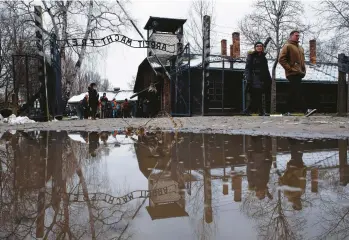  ?? MICHAL DYJUK/AP ?? Bitterswee­t anniversar­y: Visitors walk through a gate Thursday at the former Nazi death camp Auschwitz-birkenau in Oswiecim, Poland. More than 1.1 million people, mostly Jews, were killed there. Camp survivors gathered Friday to mark the 78th anniversar­y of its liberation, amid horror that yet another war has shattered peace in Europe.