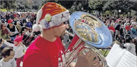  ??  ?? Matt Naylor of Austin makes music during the annual Tuba Christmas performanc­e held on the south steps of the state Capitol in Austin on Friday. See more photos from Merry Tuba Christmas Austin online at