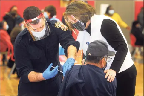  ?? Ned Gerard / Hearst Connecticu­t Media ?? Nurse Elin Loh assists Lt. Ken Benedict of the Bridgeport Fire Department as he administer­s a COVID-19 vaccinatio­n to a man at the weekly vaccinatio­n clinic held at Central High School in Bridgeport on Feb. 10.