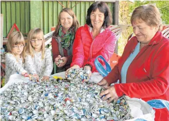  ?? FOTO: TOBIAS REHM ?? Alle Hände voll zu tun: Die Mitglieder der Wanderfreu­nde Sinningen, Melanie Liebscher (v. l.) mit Jana und Nora, Elisabeth Kuß und Rosmarie Guter, an einem der mit Kronkorken gefüllten Säcke.