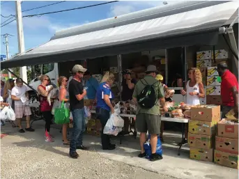 ??  ?? Volunteers distribute bread and other foods at one of the Harry Chapin Food Bank’s Coastal Relief Campaign mobile pantries, set up to aid those impacted by the red tide and blue-green algae crisis in 2018.