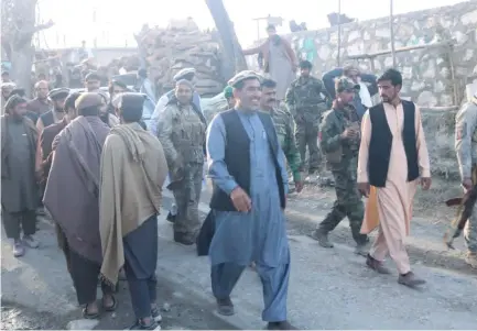  ?? (Reuters) ?? NANGARHAR PROVINCIAL OFFICIAL Ajmal Omar (in blue) walks with soldiers from the government of former President Ashraf Ghani in this undated photo obtained by Reuters.