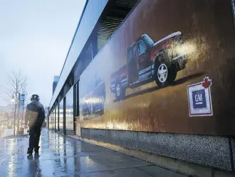  ?? COLE BURSTON/BLOOMBERG ?? A pedestrian walks past a GM mural in downtown Oshawa, Ont., on Monday. The job cuts there and in the U.S. are partly attributed to U.S. steel tariffs.