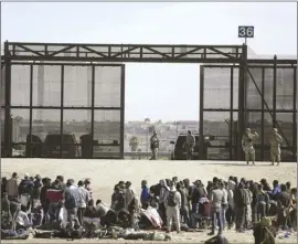  ?? AP file photo ?? Migrants who crossed the border from Mexico into the U.S. wait next to the U.S. border wall where U.S. Border Patrol agents stand guard, seen from Ciudad Juarez, Mexico on March 30.