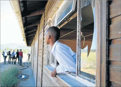  ?? Picture: SISIPHO ZAMXAKA ?? SHAMELESS: A pupil at Vukile Tshwete High School, in Keiskammah­oek, outside King William’s Town, looks out of a broken window during a visit by Equal Education. Vukile is one of the schools that does not meet norms and standards as set out by the...